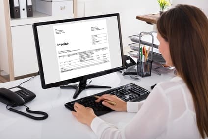 Businesswoman Looking At Invoice On Computer